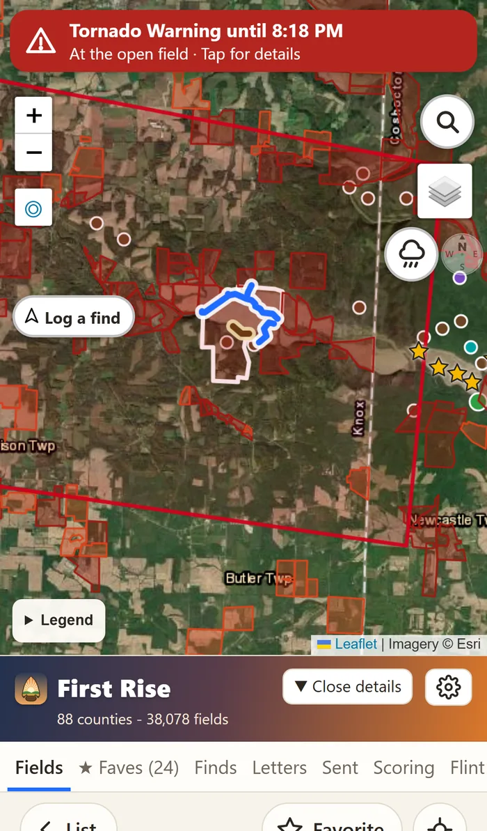 The app on a phone with a red Tornado Warning banner across the top of the map and the warning's red outline drawn around the field.